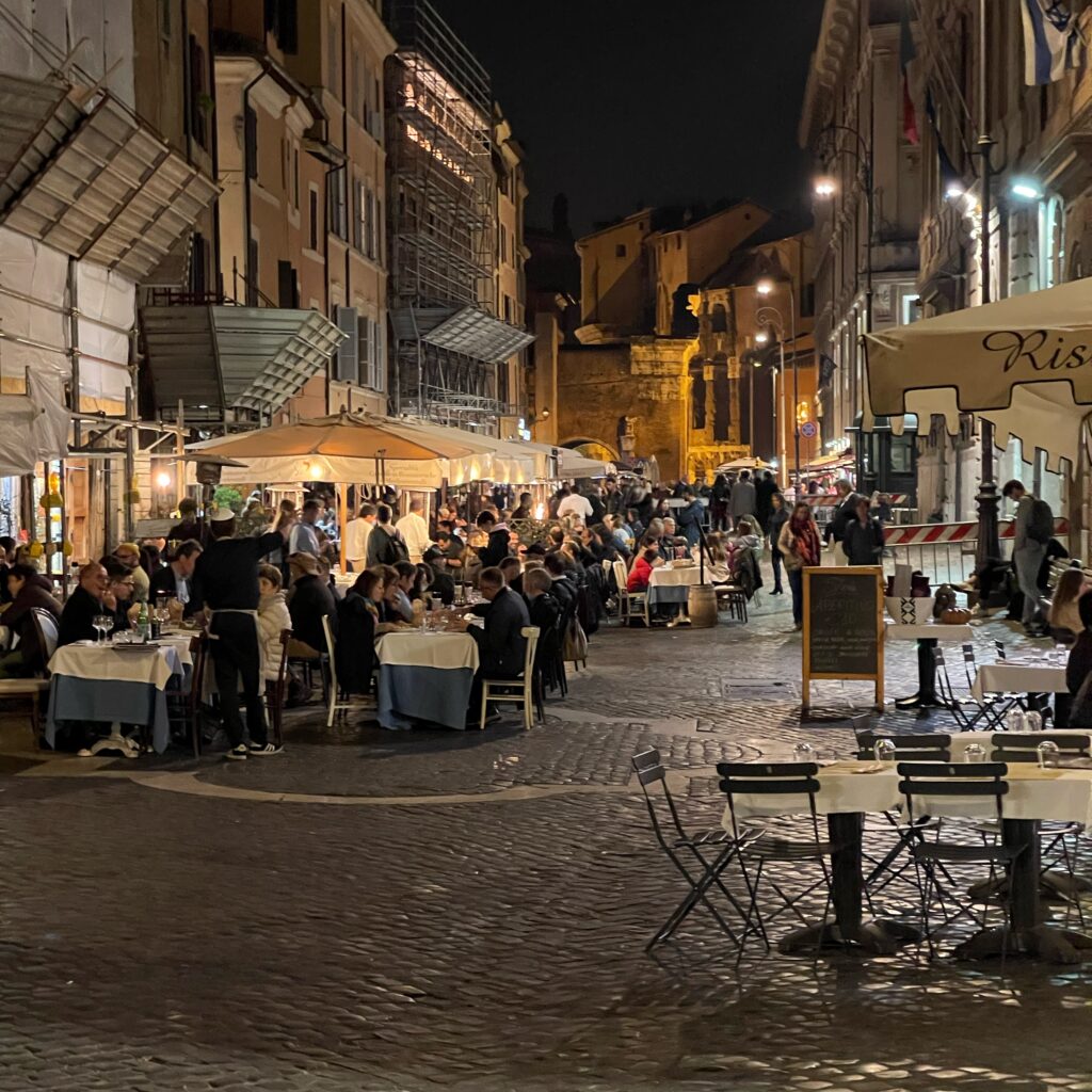 Nachts im Jüdischen Ghetto. Unzählige Restaurants haben Tische und Stühle auf die Straße gestellt. Menschen sitzen dort und essen.