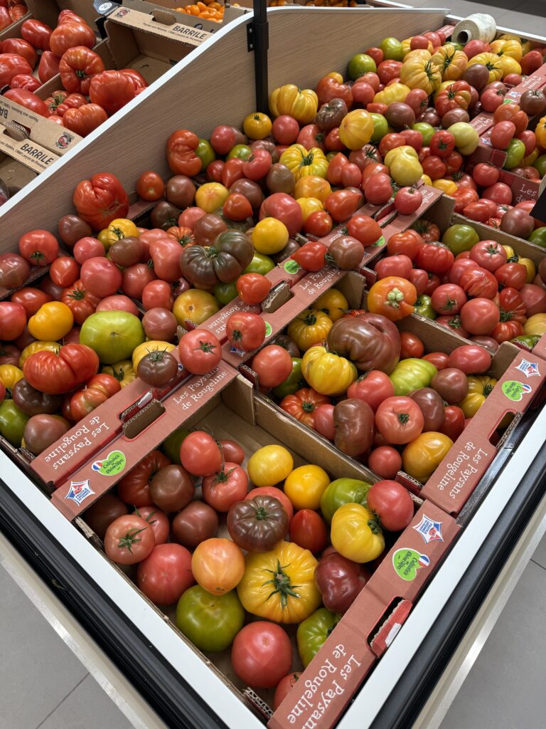 Mehrere Kisten mit bunten Tomaten in einem französischen Supermarkt.