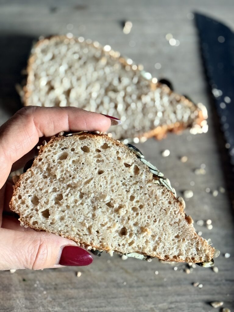 Eine Hand hält ein aufgeschnittenes Brötchen. Man sieht die porige Struktur.